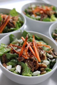 four white bowls filled with salad on top of a table