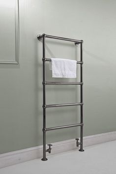 a towel rack in the corner of a room with green walls and white flooring