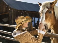 a woman petting the nose of a horse