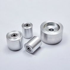 three metal rollers on a white surface with one bearing and the other bearing an object