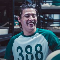 a young man laughing while wearing a green and white shirt