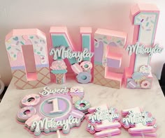 a table topped with lots of cake and cupcakes next to the letter m