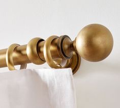 an image of a curtain rod with gold knobs on the top and white drapes