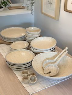 a table topped with lots of white plates and bowls