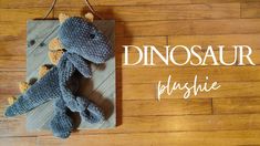 a crocheted dinosaur hanging on a wooden sign