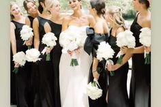 a group of women standing next to each other holding white and black flowers in their hands