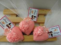 three pink baby shoes with bows and tags attached to them on a wooden rack for display