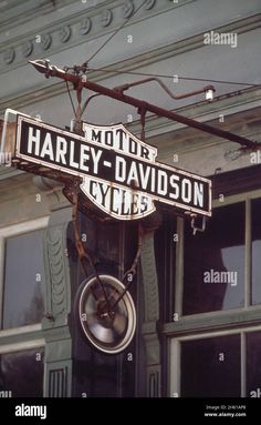 a street sign hanging from the side of a building in front of a window - stock image