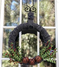 a wreath with basketballs hanging from it in front of a window, decorated with greenery