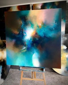 an abstract painting on easel in front of two large canvases with different colors