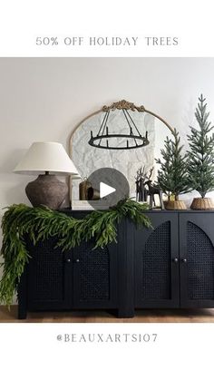 a christmas tree is on top of a black cabinet with greenery in front of it