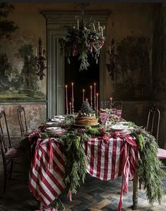 a christmas table setting with candles and greenery on the dining room table in an old house