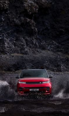 a red car is driving through some water