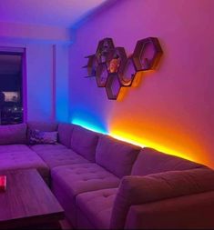 a living room with purple and blue lighting on the walls, couches and coffee table