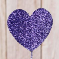 purple glitter heart shaped cake topper with water dripping from the middle, on wooden background