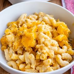 a white bowl filled with macaroni and cheese on top of a wooden table