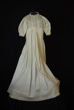 A lovely white cotton antique Christening gown dated from mid to late 1800's Victorian era. Dress is light weight cotton with tuck pleats on bodice & around hemline. It is unlined and has lace on bodice & edge of sleeves. The waist is shirred & can be adjusted  and there is a wide sash attached at front that ties at the back. The opening at the back has 5 very tiny ( 1/4" ) white buttons. It measures 19"  around chest, 7 1/2" sleeve and 35" length.  The dress is in excellent condition for age & White Cotton Regency Prairie Dress, White Cotton Regency Style Prairie Dress, Victorian Cotton Prairie Dress For Daywear, Victorian Cotton Dress With Historical Design, Cotton Victorian Dress For Daywear, Historical Prairie Dress For Daywear, White Cotton Prairie Dress For Wedding, Regency Prairie Dress With Empire Waist For Wedding, Regency Style Prairie Dress With Empire Waist For Weddings