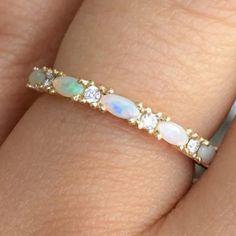 a woman's hand with an opal and diamond ring