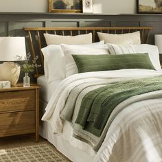 a bed with green and white comforter in a bedroom next to a night stand