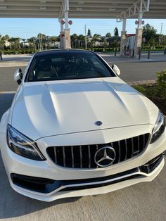 the front end of a white mercedes s - class coupe parked at a gas station