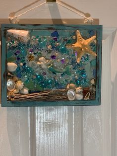 an ocean scene made out of sea glass and seashells hanging on a door