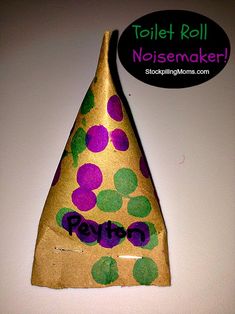 a brown paper bag with purple and green polka dots on it, next to a sign that says toilet roll noisemaker