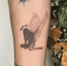 a small tattoo on the arm of a woman with stars around her body and wings