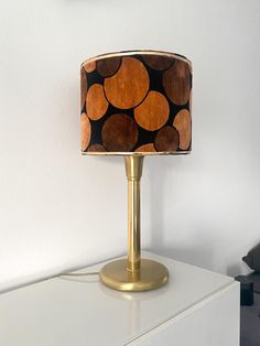 a lamp that is sitting on top of a white dresser next to a wall with a clock above it