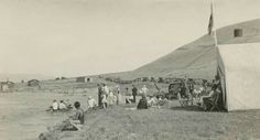 an old black and white photo of people in the water near a tent with a flag on it