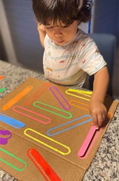 a young child is playing with some magnets on a cardboard box that he made