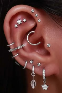 a woman's ear with stars and moon piercings