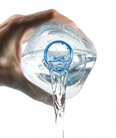 a hand holding a clear glass object in it's right hand with water pouring out of it