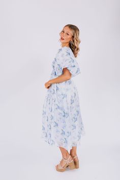 Indulge in the dreamy charm of our EXCLUSIVE Lost In A Dream Dress. Featuring a beautiful blue floral print, smocked bust, and delicate ruffle details. This midi dress is an exclusive design found only at One Loved Babe. With inclusive sizing from XS to 6XL, this dress is perfect for everyone! Details Textured fabric along bust Exaggerated puff sleeve Corset inspired Lined Invisible zipper back closure Shired back Piping details Blue floral Sizing *Measurements are taken with item hanging.* Appr Breezy Floral Print Midi Dress For Daywear, Light Blue Floral Print Midi Dress For Brunch, Flowy Light Blue Midi Dress For Daywear, Feminine Blue Floral Dress With Ruffles, Feminine Blue Chiffon Midi Dress, Blue Breezy Midi Dress For Garden Party, Breezy Blue Midi Dress For Garden Party, Light Blue Flowy Midi Dress With Floral Print, Flowy Light Blue Midi Dress With Floral Print