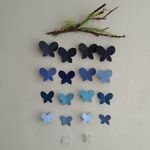 a bunch of blue and white butterflies hanging on a wall next to a twig