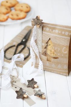 some cookies are sitting on a table next to a paper bag and pair of scissors