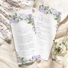 two wedding menus with purple flowers and greenery on them, next to a lace doily