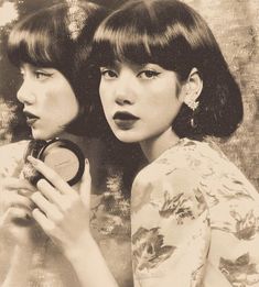 two young women are looking at each other in black and white, one is holding a compact mirror