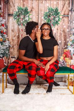 a man and woman sitting next to each other on a bench in front of a christmas backdrop