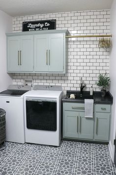 a kitchen with white cabinets and black counter tops next to a washer and dryer