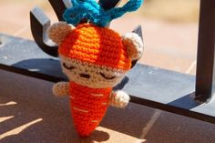 a crocheted stuffed animal that looks like a carrot is hanging from a hook