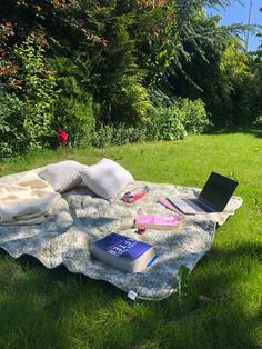 an open laptop computer sitting on top of a blanket in the middle of a field