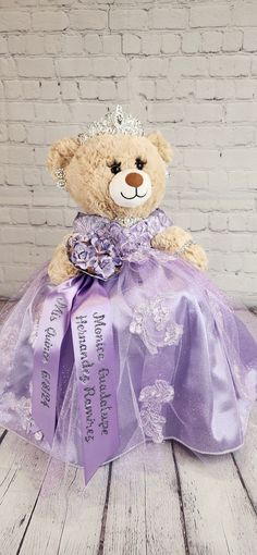 a teddy bear wearing a purple dress and tiara