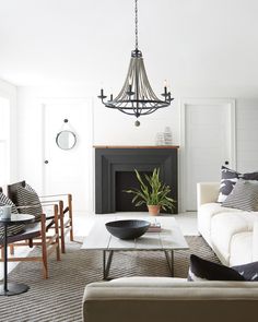 a living room filled with furniture and a chandelier hanging from the ceiling over a fire place