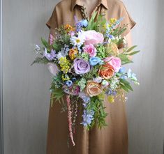 a woman holding a bouquet of flowers in front of her face and wearing a brown shirt