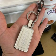 a hand holding a white leather key chain