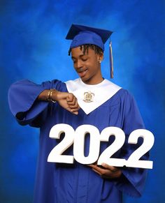 a man in a graduation gown is holding the number 22 on his cap and gown