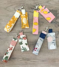 four key chains with different designs on them sitting on a wooden table next to each other