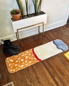 three pairs of shoes are sitting on the floor next to a potted plant and rug