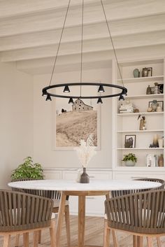 a dining room table with chairs and a vase on the table in front of it