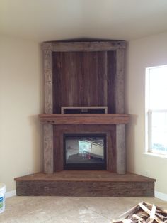 a living room with a large wooden fireplace and tv on the mantle, in front of a window